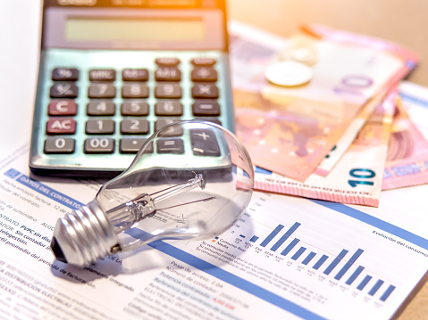 Electricity bill next to a calculator, a bulb and money. Electricity price concept.